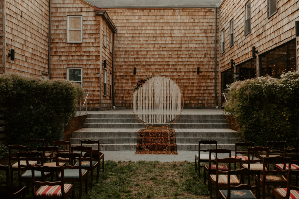 A Cincinnati wedding photograph of a Vintage-Boho wedding ceremony set up with a Macrame Altar at The Factory Events Wedding Venue in Northside, Cincinnati Ohio. 