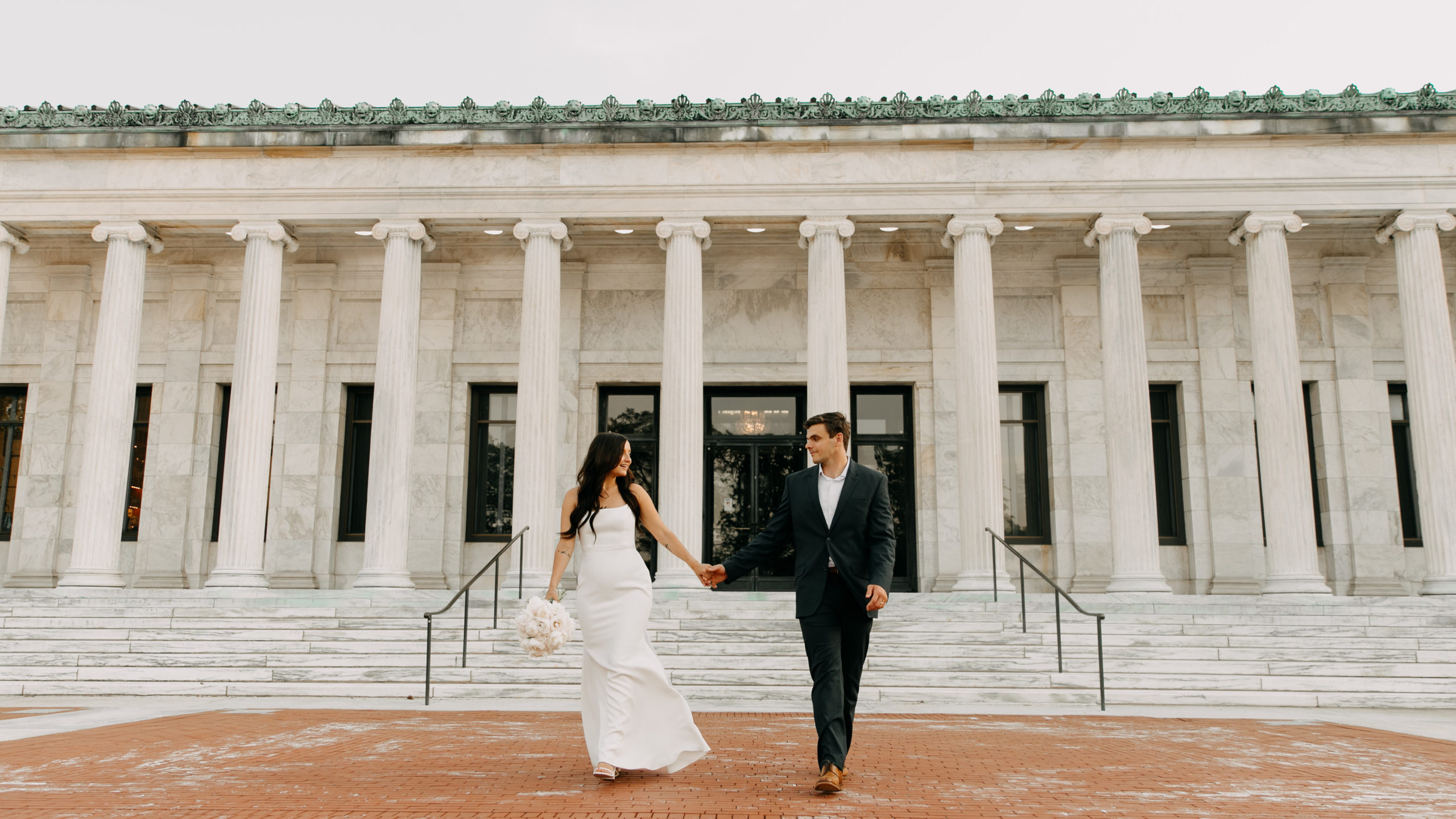 Couple walking on their wedding day in front of the Toledo Museum of Art. 