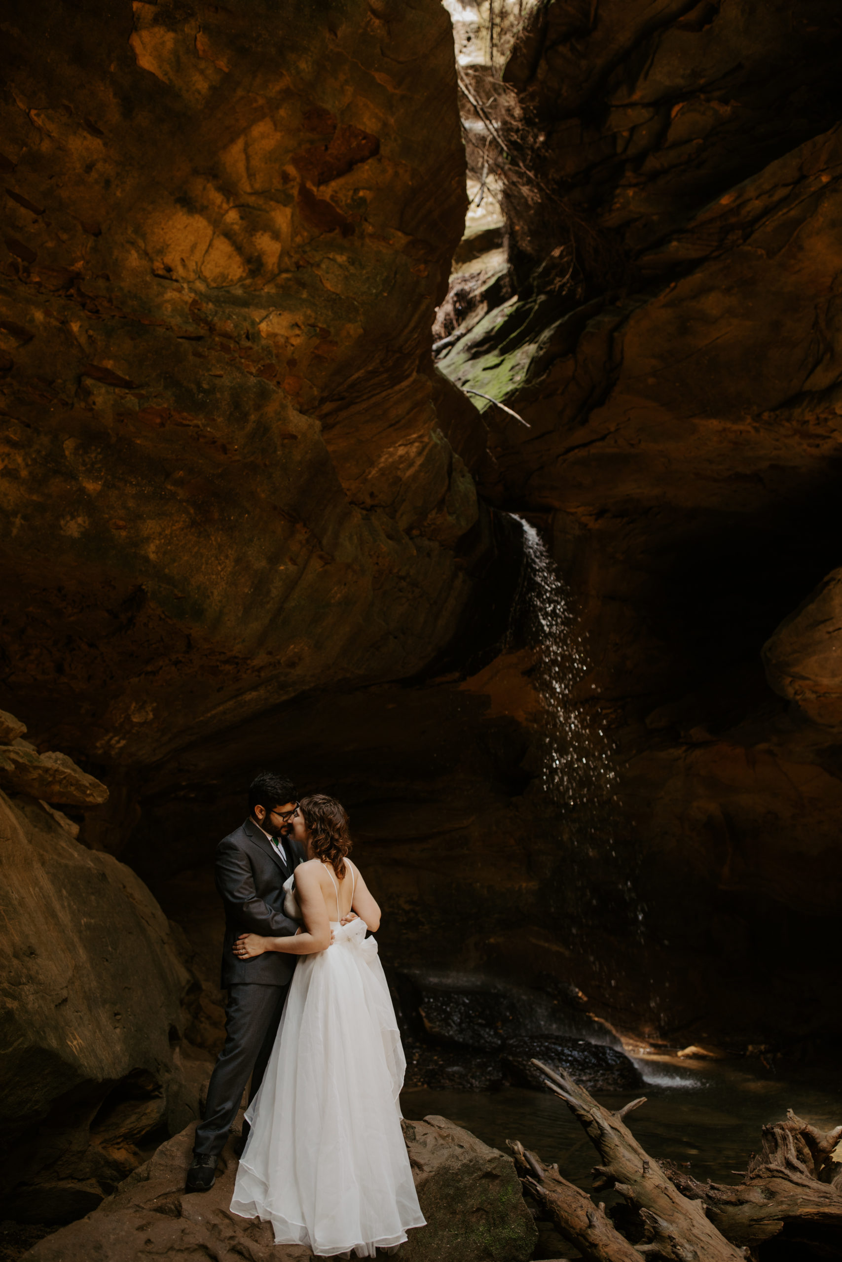 A couple at their Hocking Hills elopement having their first kiss under Conkle's Hollow waterfall.