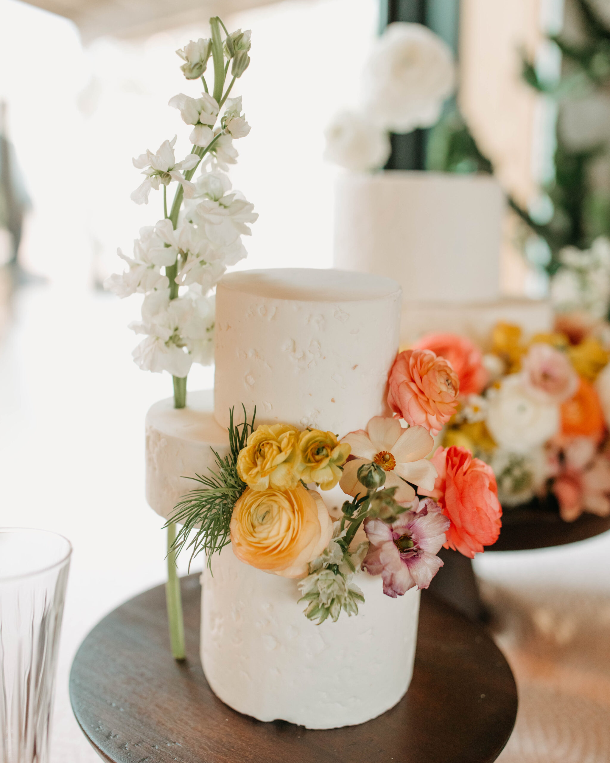 An organic structured wedding cake featuring colored florals. 
