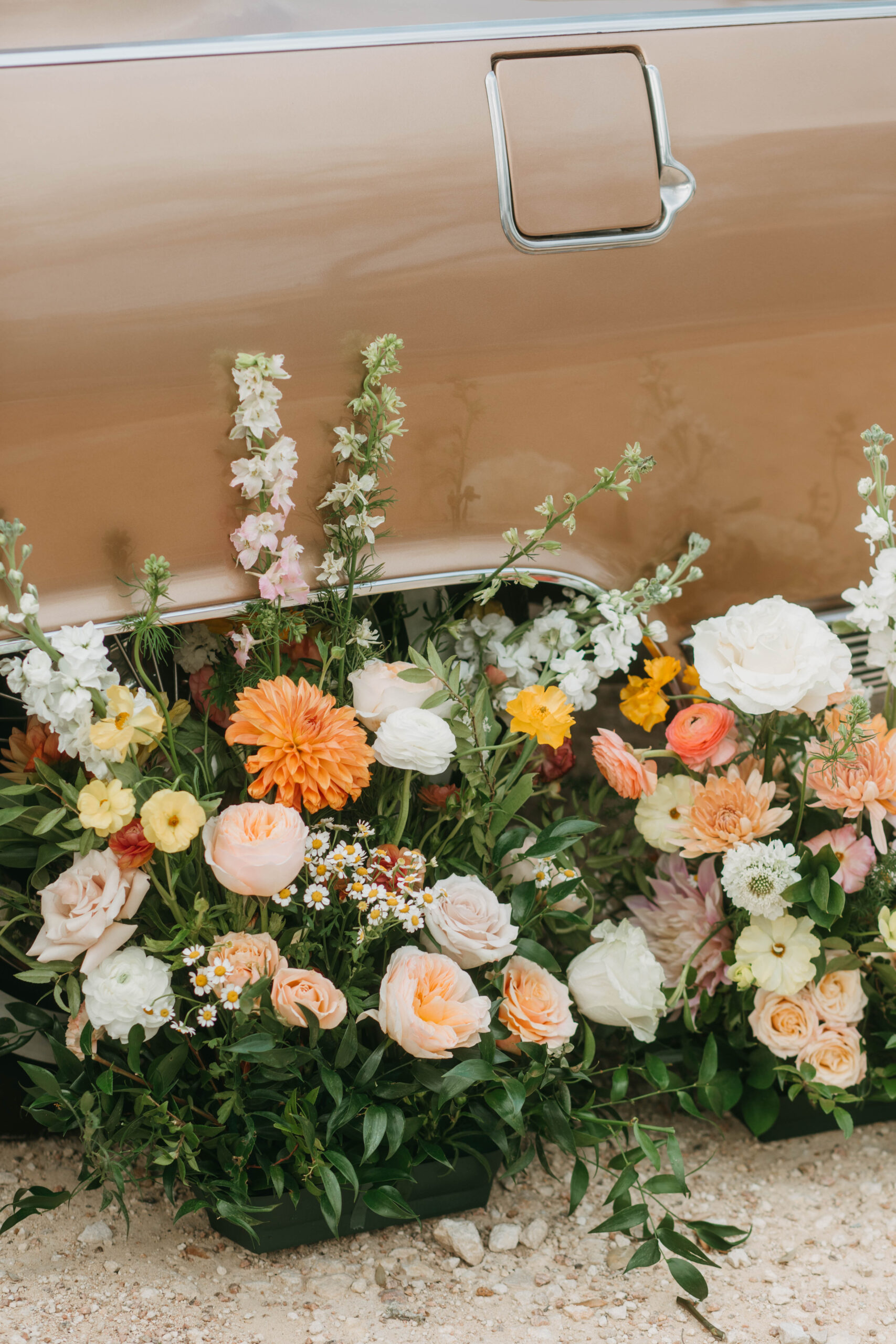 A boho flower centerpiece next to a vintage car for a wedding at Cactus Moon Lodge in Austin Texas.