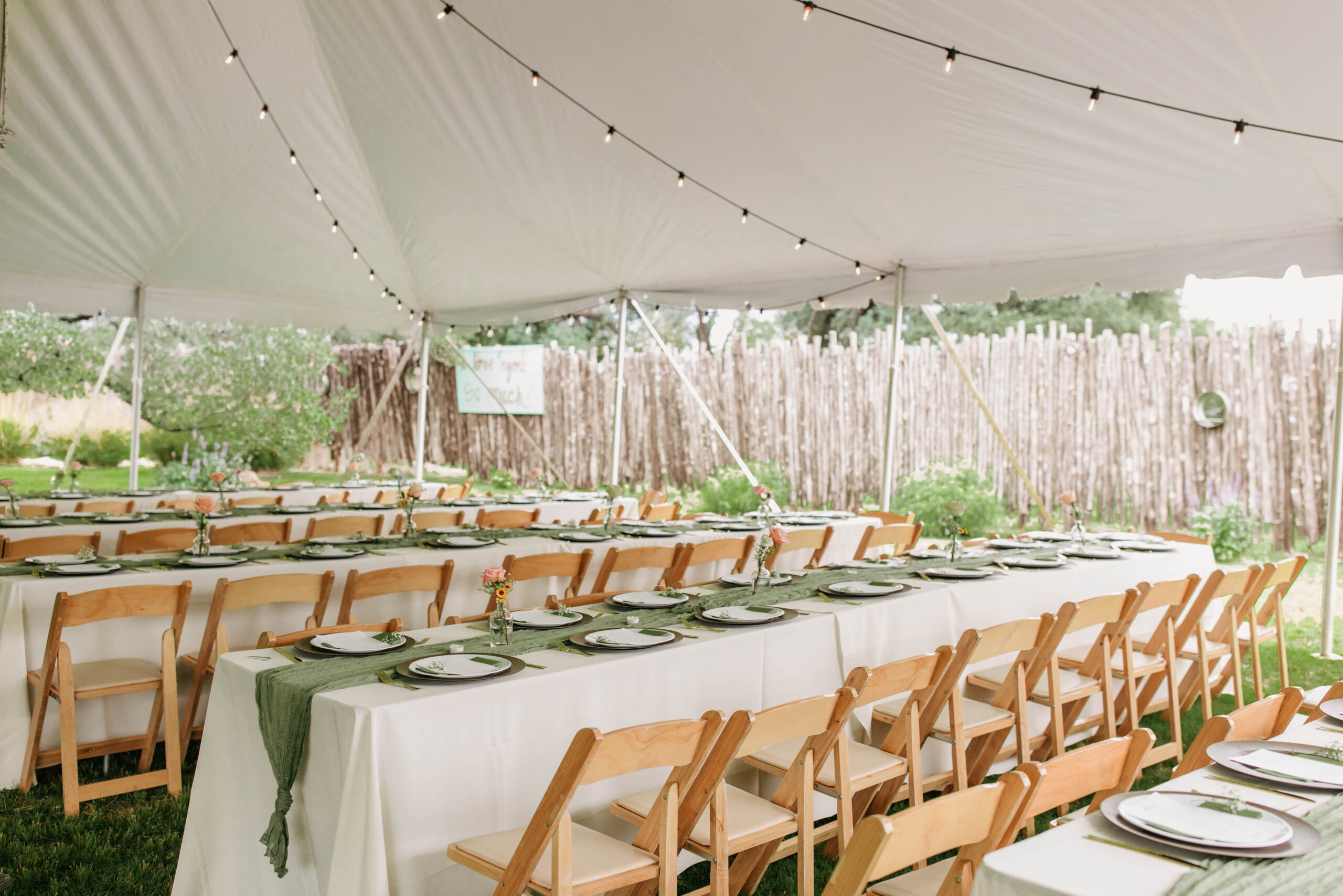 Tent Wedding Reception photo. Featuring wooden reception folding chairs with green table runners and white tablecloths. 