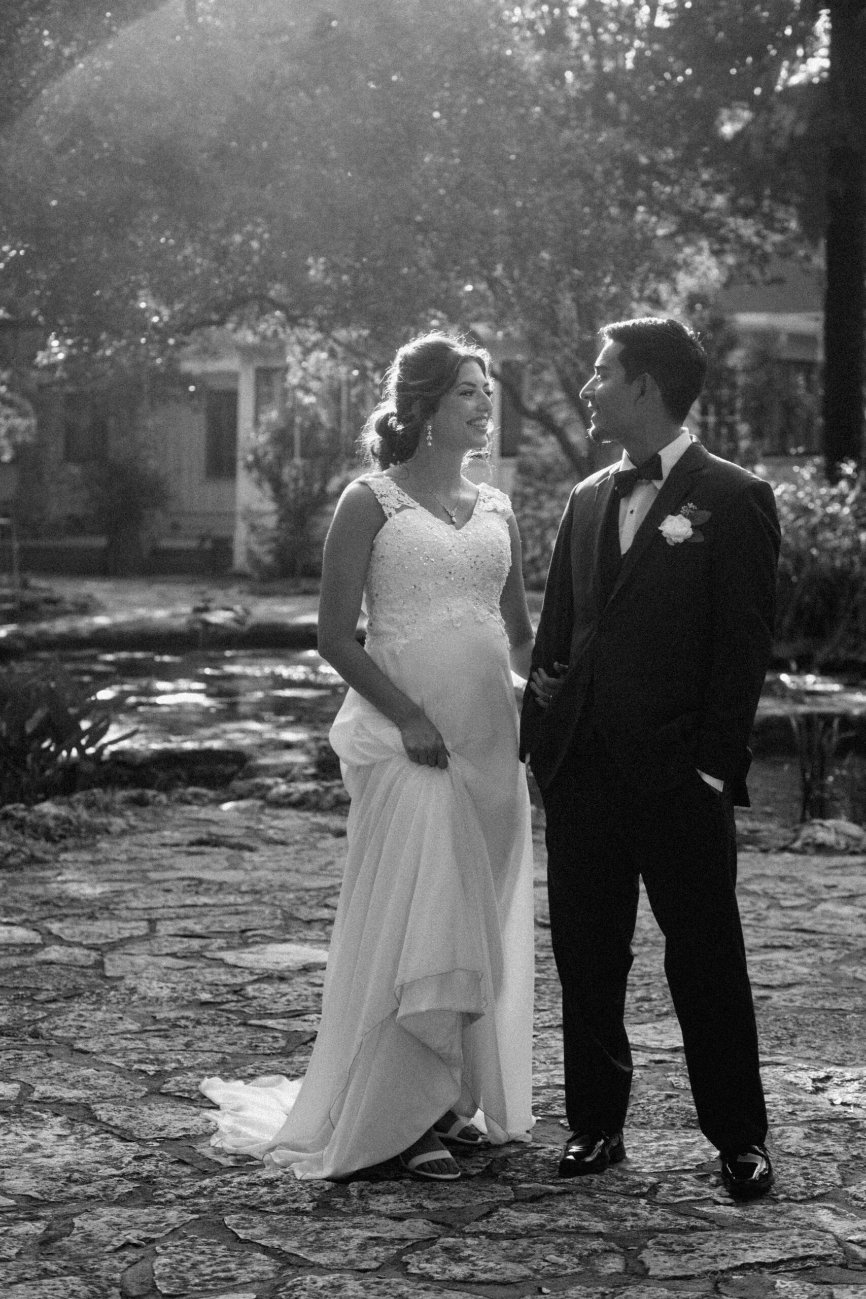 Black and white photograph of wedding couple laughing at Mayfield Gardens. 