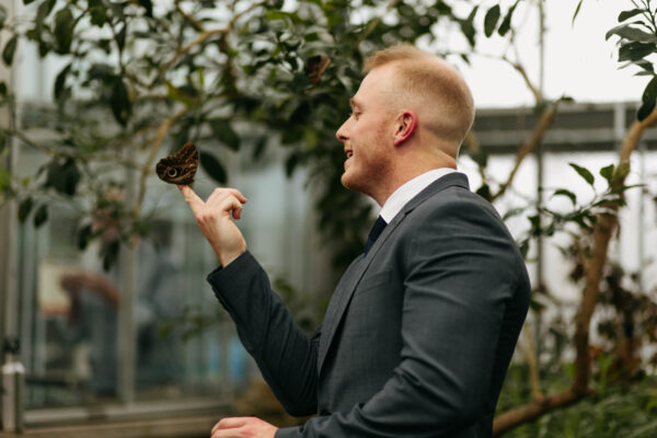 Guests catching butterfly on their hand at the Krohn Conservatory 