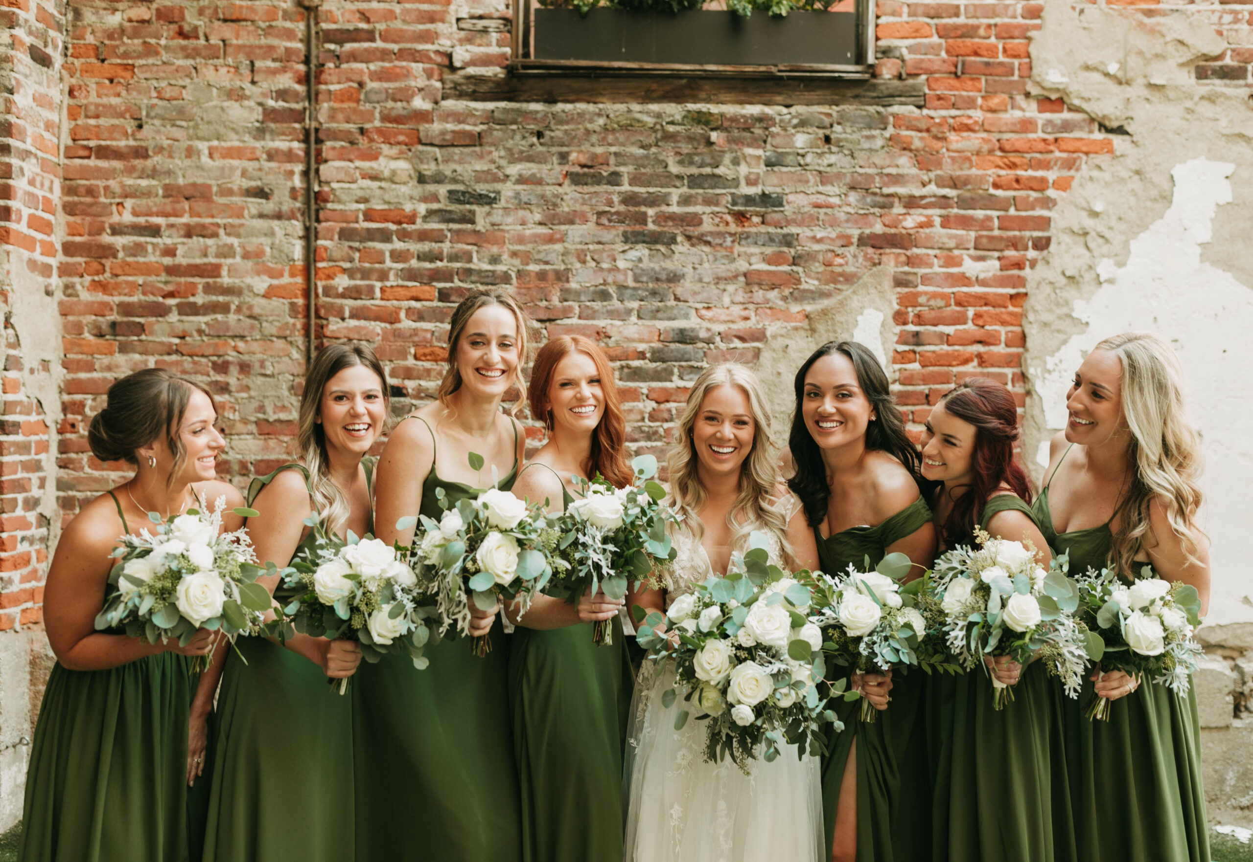 Bridal party photograph of wedding at Hotel Covington. Green bridesmaid dresses with all white and green florals! 