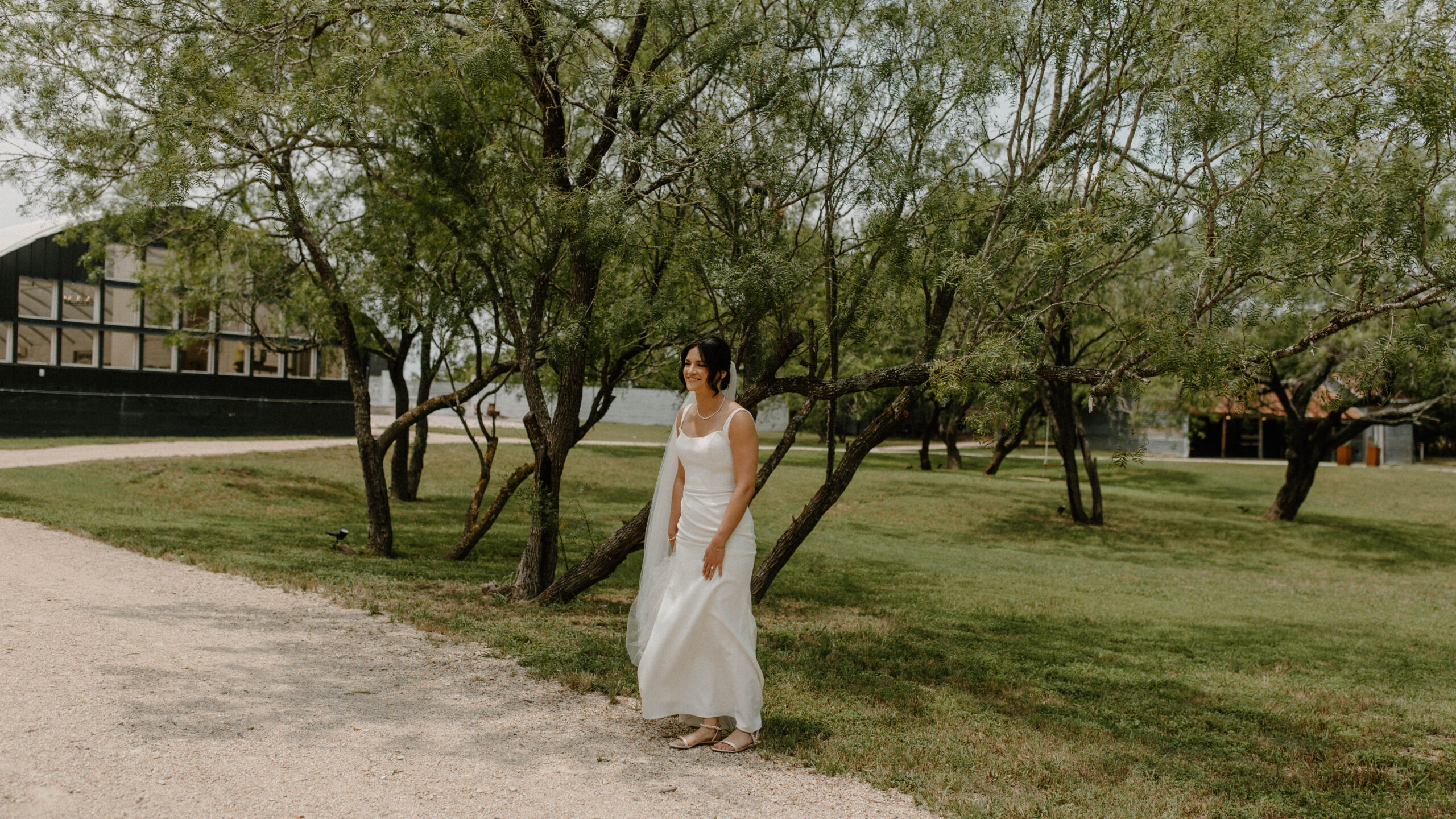 Bride standing in a tree grove at Camino Real Ranch waiting to do her wedding first look. 