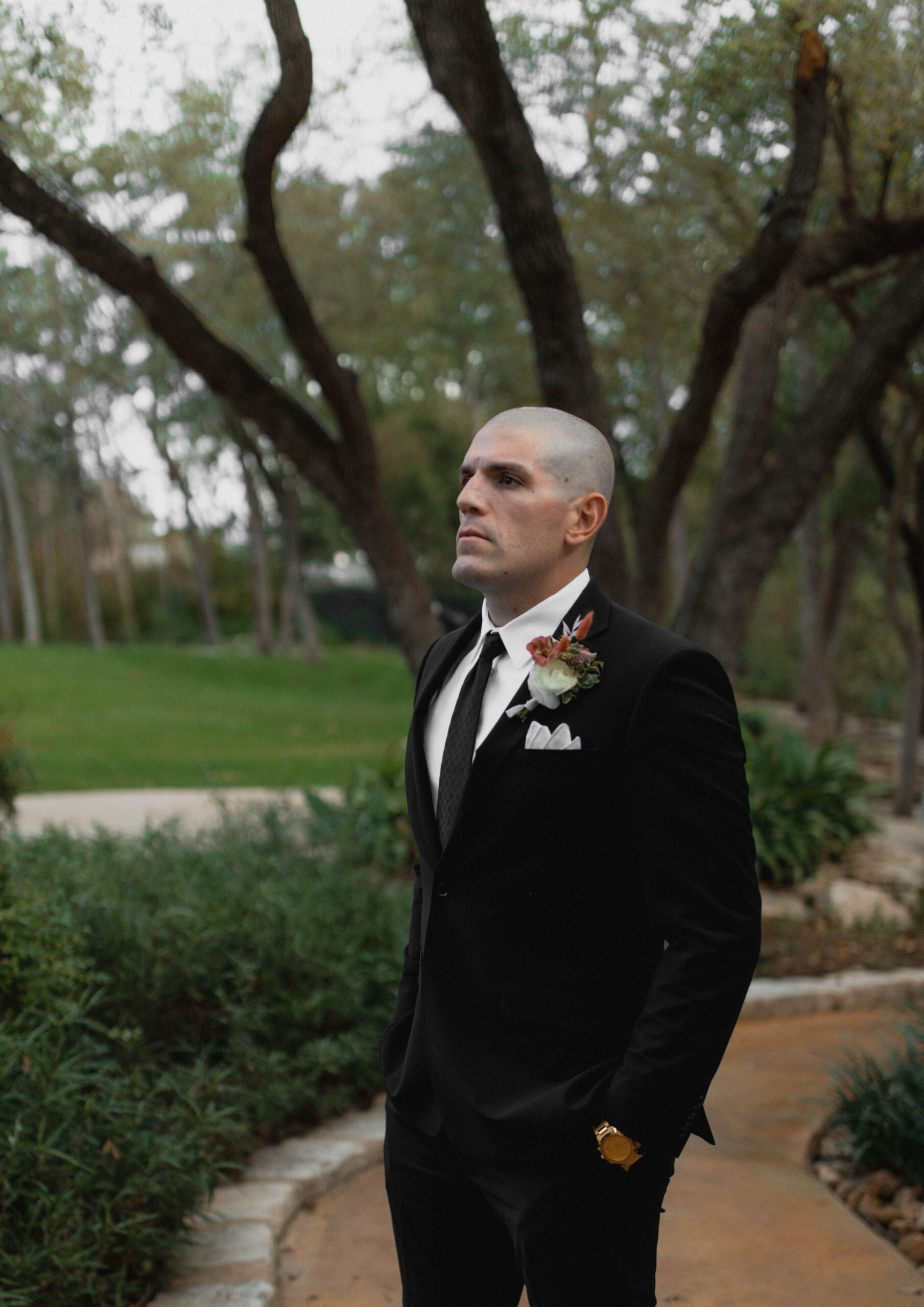 Modern groom's portraits in outdoor garden. All black suit with black tie inspiration photo. 