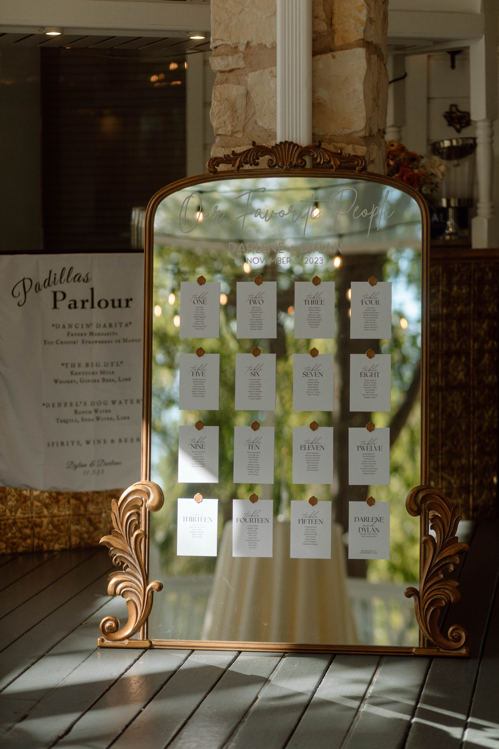 A wedding reception seating chart on an antique mirror with gold stamps. 